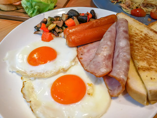 American breakfast with fried eggs, sausages, ham, toasted bread and vegetables. Easy, fast cooking food in rush hour. Most popular breakfast always serve in the morning around the world.