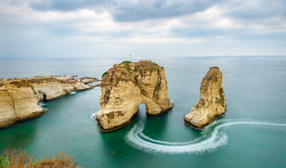 Fototapeta premium Rouche skały w Bejrucie w Libanie w pobliżu morza i podczas zachodu słońca. Pochmurny dzień w Bejrucie w Libanie na Pigeon Rocks na Morzu Śródziemnym.