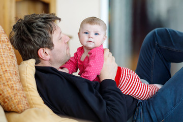 Happy proud young father with newborn baby daughter, family portrait together