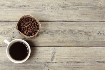 Cup of coffee and beans on wooden background