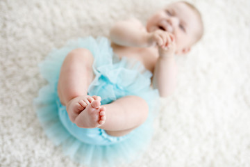 Close-up of legs and feet of baby girl on white background wearing turquoise tutu skirt. © Irina Schmidt