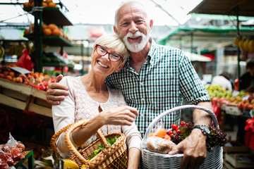 Smiling senior couple buying vegetables and at the merket