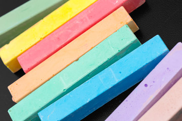 Set of colored chalks over a black background