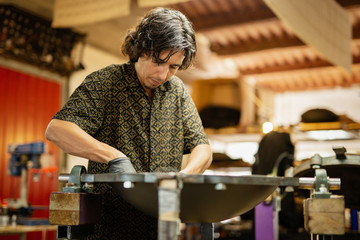 Craftsman in his workshop making design and construction of Handpan, a metal percussion instrument.