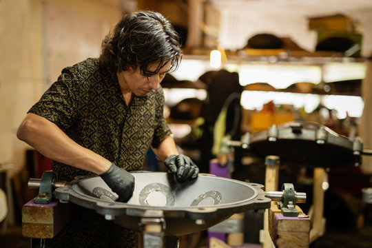 Craftsman designing handpan iCraftsman in his workshop making design and construction of Handpan, a metal percussion instrument.nstrument