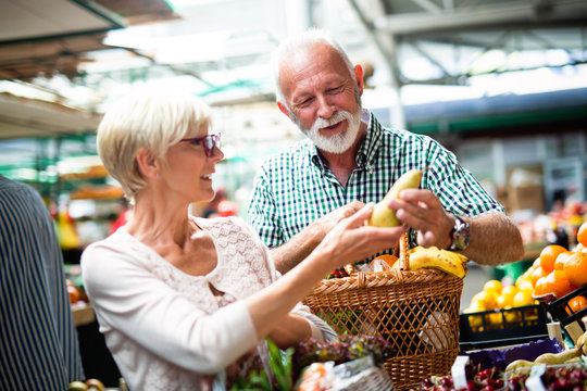 Senior family couple choosing bio food fruit and vegetable on the market during weekly shopping