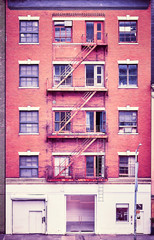 Vintage toned photo of a building with fire escapes in New York City, USA.