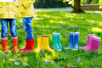Little kids, boys or girls in jeans and yellow jacket in colorful rain boots