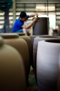 Closeup picture of traditional clay pottery in the factory with blurred worker working in background