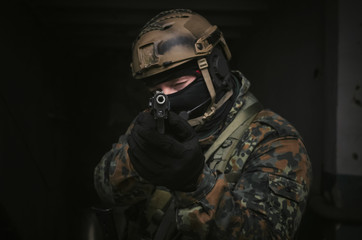 A army soldier takes aim with a pistol gun in his hands to the screen. Storming the building...