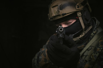 Plakat A army soldier takes aim with a pistol gun in his hands to the screen. Storming the building concept. Front view.