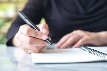 Closeup image of hands writing on blank notebook on the table