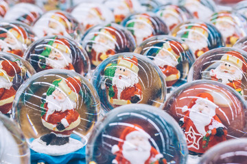 A lot of Christmas snow globes with Santa Clauses inside on the market. Christmas mood. Shopping
