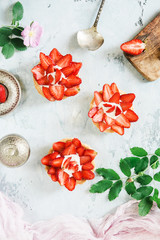 Cakes with strawberries and cream on a gray background. Composition of summer dessert with berries