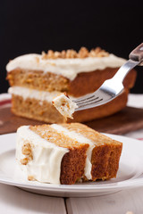 carrot cake with cream cheese and nuts on a wooden background