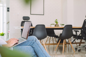 Closeup image of woman using and typing on laptop keyboard while sitting in office