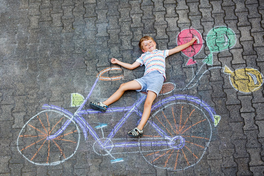little kid boy having fun with bicycle chalks picture on ground