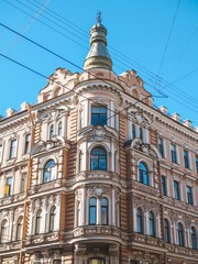 The facade of the historic old building with sculptures is against the background of blue clear sky in St. Petersburg
