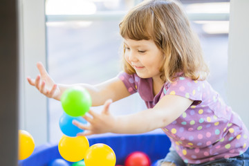 Fototapeta na wymiar Happy little girl child in colourful plastic balls pool.