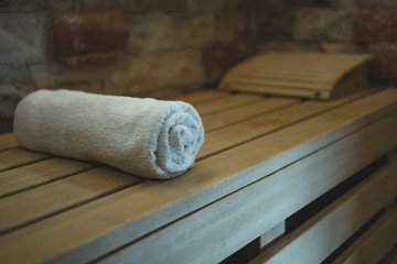 An individual cotton towel on a wooden bench prepared for a sauna client. Comfortable classical...