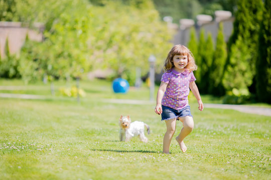 Cute little girl playing and running with small dog (terrier) outdoors