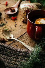 Obraz na płótnie Canvas Details of still life in the living room home interior. Beautiful cup of tea with spices and sweaters on a wooden background. Cozy autumn-winter concept