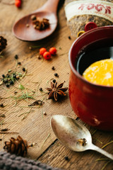Details of still life in the living room home interior. Beautiful cup of tea with spices and sweaters on a wooden background. Cozy autumn-winter concept