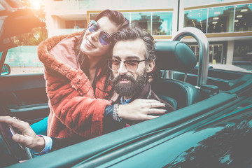 Fashion couple inside convertible car going for city tour
