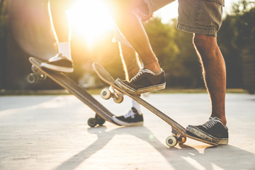 Skater friends training with skateboard at sunset outdoors