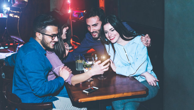 Happy Friends Using Mobile Phones In Jazz Cocktail Bar