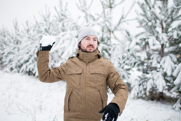 Attractive young man playing snowballs