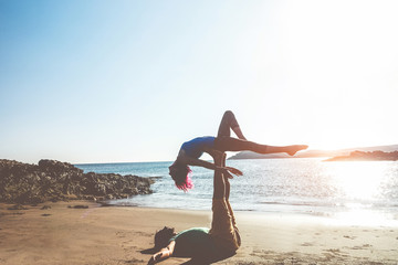 Silhouette of fit couple doing acroyoga outdoor on the beach