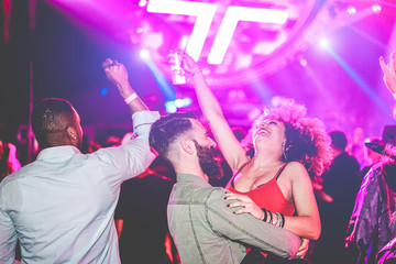 Crazy millennials friends dancing and drinking cocktails in night club