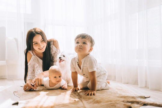 mother lying on floor with children and bichon dog