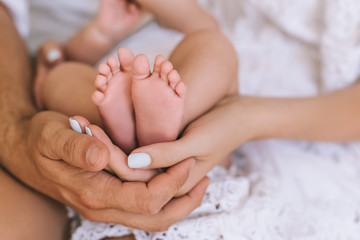 cropped shot of parents holding infant baby together