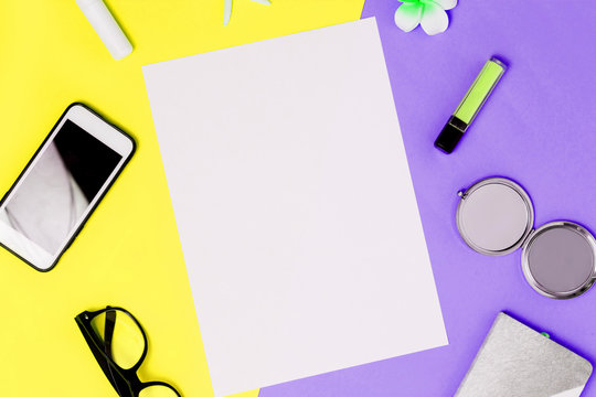 White A4 blank frame on a colorful yellow and purple background with smartphone, mirror, lipstick, glasses, Notepad