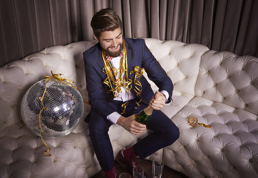 Cheerful man opening a champagne