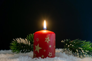 Burning Christmas candle in the snow
