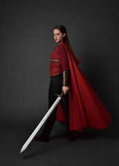 full length portrait of brunette girl wearing red medieval costume and cloak. standing pose  with...