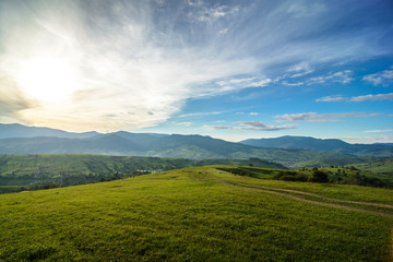 Meadows with horses, a village and a view of the mountains (Ukrainian Carpathians). Sunset landscape with beautiful clouds