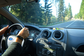 A man driving a car during a country trip through the woods and mountains