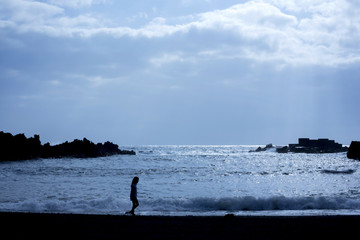 backlight of girl walking on the beach and sky with clouds