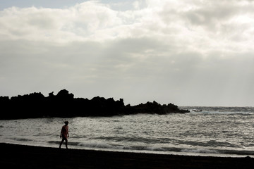 backlight of woman walking on the beach and sky with clouds