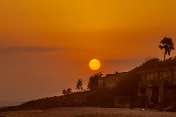 Foto op Canvas Fel oranje ondergaande zon boven het strand van Cape Coast, Ghana © Frank