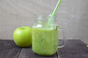 Green healthy smoothie in glass jar: banana, kiwi, green apple on rustic background