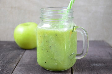 Green healthy smoothie in glass jar: banana, kiwi, green apple on rustic background