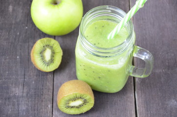 Green healthy smoothie in glass jar: banana, kiwi, green apple on rustic background