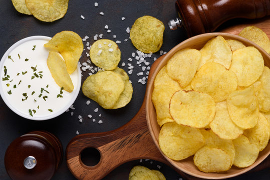 Crispy Potato Chips In Bowl With Dip And Salt On Dark Table Top View