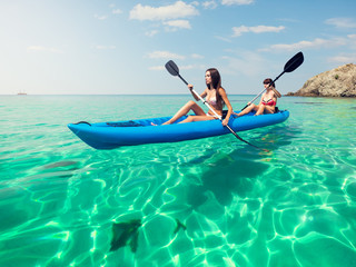Two young women kayaking in the sea. Beautiful woman canoeing on the island on a summer day.