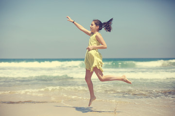 12 years old girl teen girl in yellow dress walking on seaside. Summer vacation